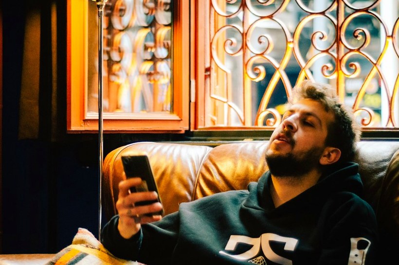 A man on a couch at night, phone in hand